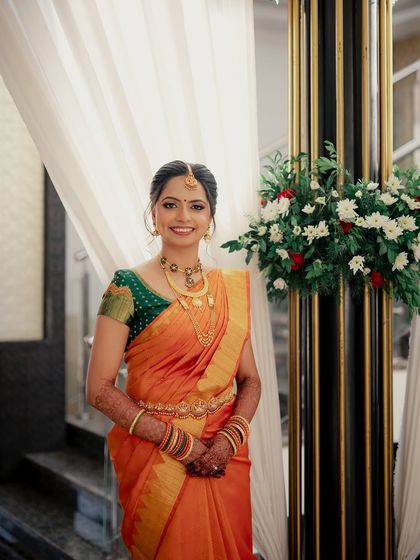 A full-length portrait of this bride, her orange and green saree creating a beautiful contrast.