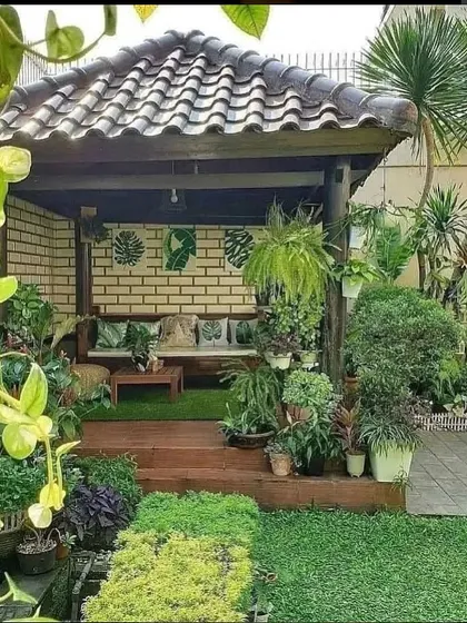 An inspirational image of a cozy, covered backyard patio, filled with a dense arrangement of potted plants, creating a perfect Balinese-style outdoor living room.