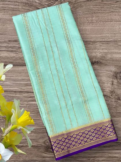 A lovely pastel sea green pure crepe Mysore silk saree with delicate gold stripes and a contrasting purple border.
