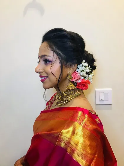 A side view of the reception hairstyle. This soft, romantic bun is adorned with fresh flowers, adding a touch of elegance to the overall look.