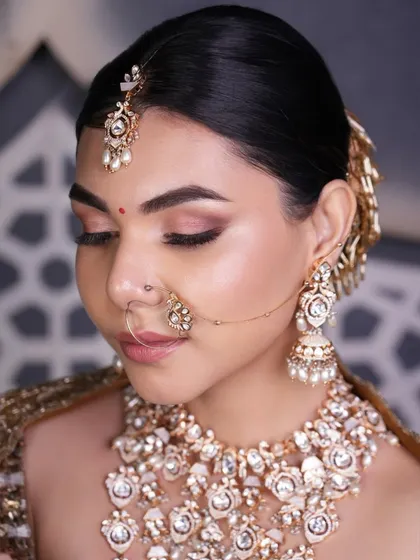 A side profile of a classic bridal bun, highlighting the smooth finish and the placement of a golden hair accessory that adds a touch of traditional glamour.