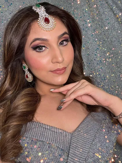 A close-up of the party look, showing the detailed eye makeup and the soft, face-framing waves. The glittery background adds to the festive feel of the look.