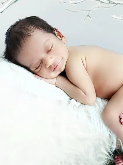 A simple and serene close up portrait of a sleeping newborn, resting peacefully on a soft white fur blanket. This pose highlights their delicate features and peaceful expression.
