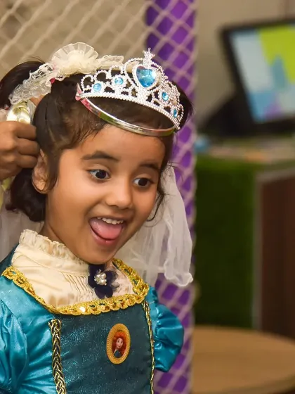 The look of pure excitement while getting dressed up as a princess, complete with a tiara and braids.