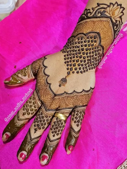 A stylish back-of-hand design using negative space to create a scalloped shape. The design is completed with a dangling jhumka (earring) motif.