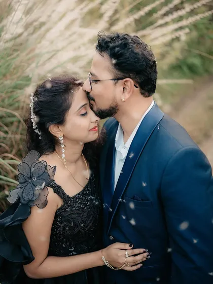 A gentle forehead kiss amidst tall grass. The soft focus and natural elements add to the romantic feel of this portrait.