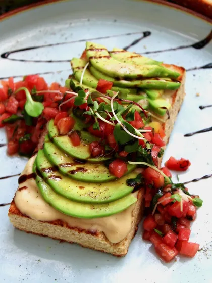 Our Exotic Open Avocado Toast is a connoisseur's dream. It features flavorful focaccia bread with a lavish spread of hummus, avocados, and zesty tomato salsa, blending Lebanese and Mexican cuisines.
