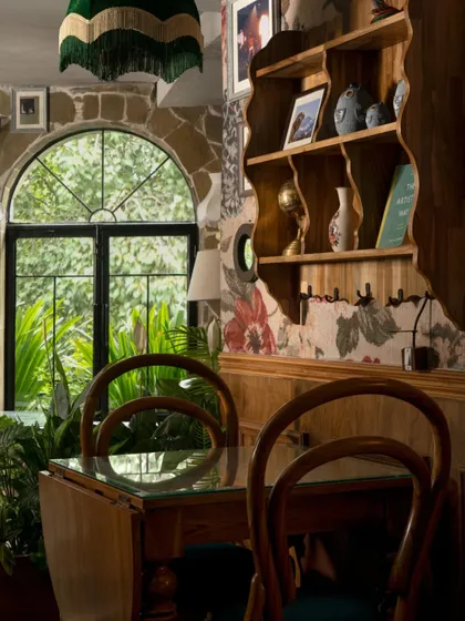 Inspired by the client's vision of a Himalayan café, we used traditional rubble walls and warm wooden interiors to bring the soul of the mountains to the city. This corner, with its arched window and eclectic furniture, feels like a cozy hilltop retreat.