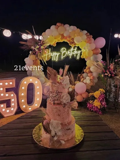 I also design elegant outdoor setups for milestone birthdays. This 50th birthday celebration featured a rustic boho theme with a balloon arch in warm tones, a 'Happy Birthday' neon sign, and large marquee numbers, creating a magical evening ambiance.