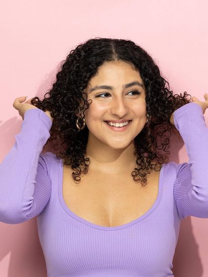 This shot is all about celebrating natural curls. The model's joyful expression and beautifully defined hair instantly communicate the effectiveness of the hair care products she's using.