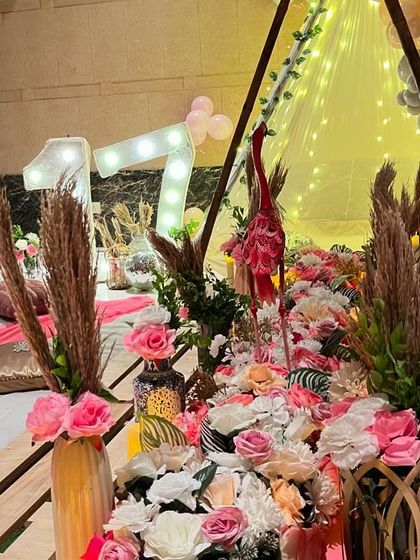 A close-up of the beautiful tablescape for the boho picnic, featuring pink roses, pampas grass, and flamingo props.