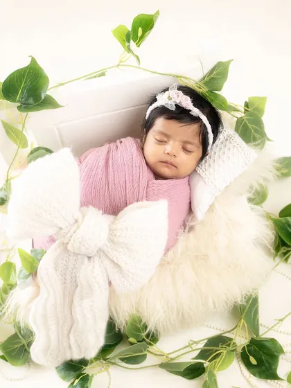 A gift of love, tied with a giant knitted bow. This creative shot places the baby in a gift box, surrounded by greenery for a whimsical touch.