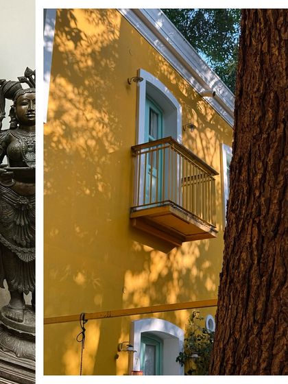 A sunny yellow wall with a charming balcony, the shadows of a tree creating a beautiful pattern across the facade.