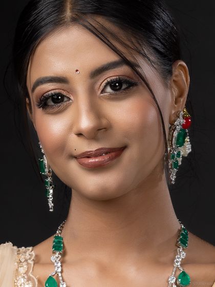 A close-up portrait focusing on the model's gentle smile and the intricate details of her traditional Indian jewellery.