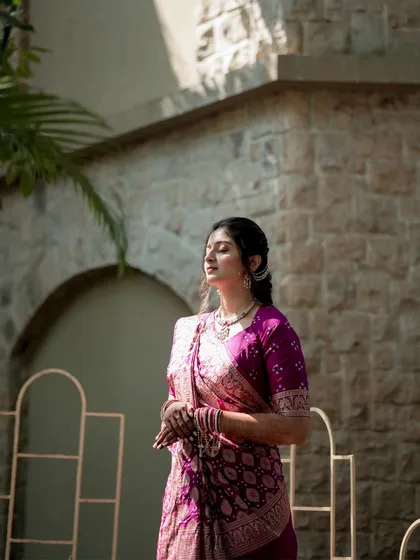 Bathed in sunlight and grace. This bride, dressed in a beautiful purple bandhani saree, seems to be soaking in the significance of the moment. It's a portrait of tranquility and elegance.