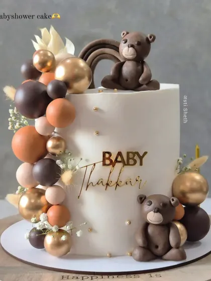 A neutral-toned baby shower cake with adorable, handcrafted teddy bears. The balloon cascade in shades of brown, beige, and gold creates a warm, modern look.