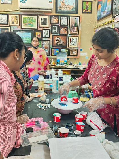 Students gathered around a table, learning the fundamentals of mixing colors for a fluid art piece in our resin workshop.