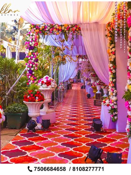 A long, colorful walkway for a grand wedding. The path is lined with floral arrangements and covered with draped fabric, creating a beautiful and immersive experience for guests.