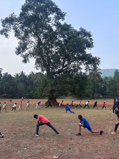 Participants engage in morning warm-up stretches in a large circle at our Dandeli camp, getting ready for an action-packed day.