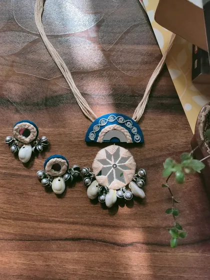 This handcrafted mirror work necklace set is made with a combination of fabric, thread work, and cowrie shells. The design is inspired by traditional Gujarati jewelry, perfect for garba nights.