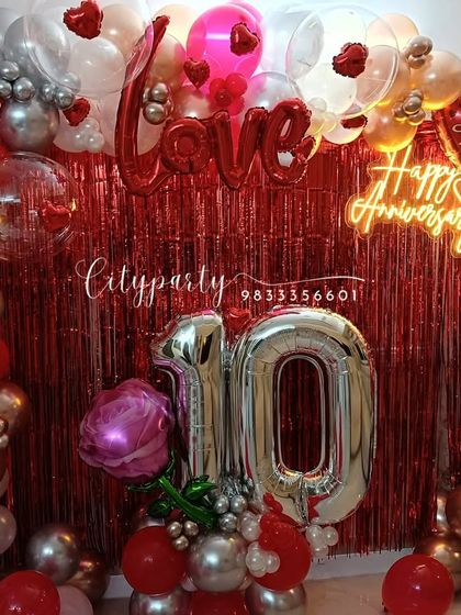 A focused shot of the anniversary balloon arch, showing the mix of red, white, and silver balloons, transparent balloons with hearts inside, and 'Love' foil letters.