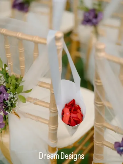 Love is in the details. A simple paper cone filled with fresh rose petals hangs from a chair, ready for guests to shower the couple during their exit.