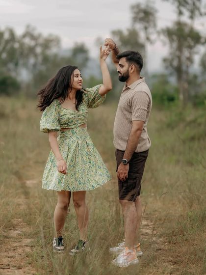 A playful, jumping shot of a couple in a grassy field, capturing their fun-loving energy.