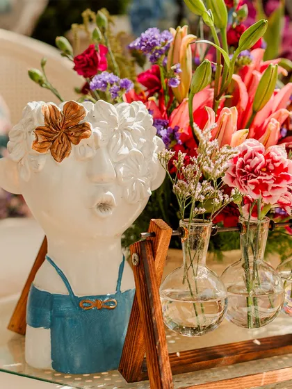 A quirky and artistic centerpiece featuring a ceramic face vase. I love incorporating unique decor items that reflect the couple's personality and add a playful touch to the ambiance.