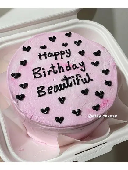 A pretty pink bento cake with 'Happy Birthday Beautiful' written on it, decorated with contrasting black hearts.