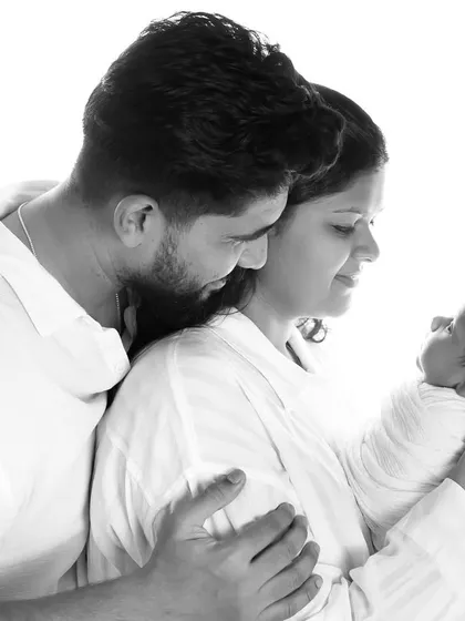 This is how you make memories that last forever. A beautiful, light-filled portrait of new parents gazing at their precious baby.