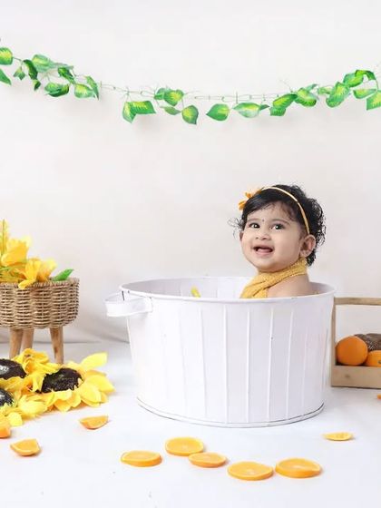 A simple and clean bathtub setup with a personalized chalkboard. This toddler is enjoying a playful moment in the tub, surrounded by sunflowers.
