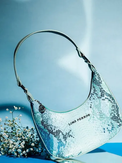 A single bag from the same series, shot to look as if it's floating. The minimalist composition with a touch of baby's breath flowers is elegant and eye-catching.
