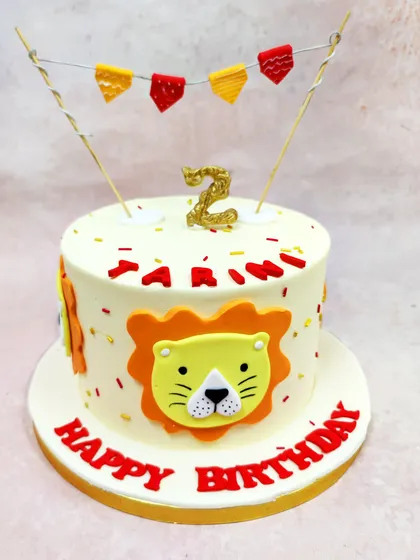 This cheerful Cartoon Lion Face Cake is perfect for a toddler's birthday, featuring a friendly lion, a festive banner, and a personalized name.