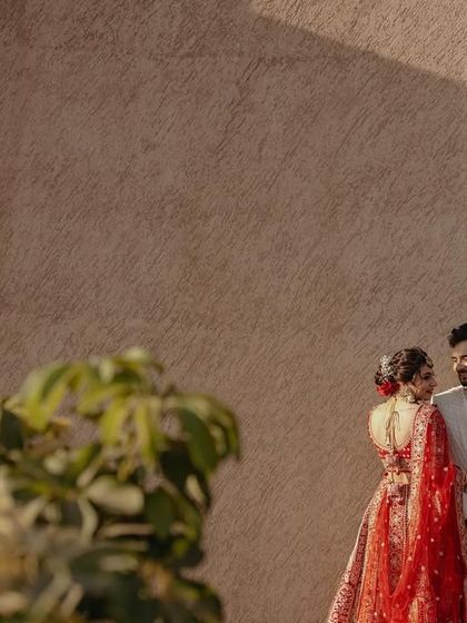 An artistic shot of the couple, framed by greenery, creating a sense of intimacy and privacy.