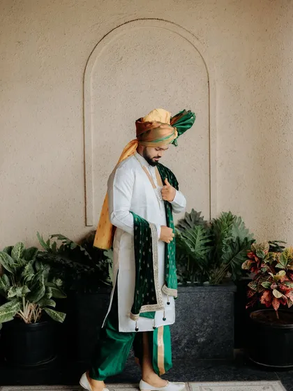 A full-length portrait of the groom, adjusting his attire. This shot captures the quiet moments of preparation and anticipation on the wedding day.