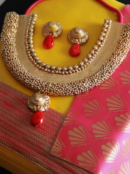 A detailed view of the edible necklace and earrings, complete with tiny beads and a red stone drop, all made from fondant and sugar.