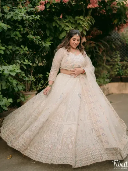 A full-length shot showcasing the bride's stunning white lehenga. The makeup was kept elegant and timeless to complement the intricate embroidery of her outfit.