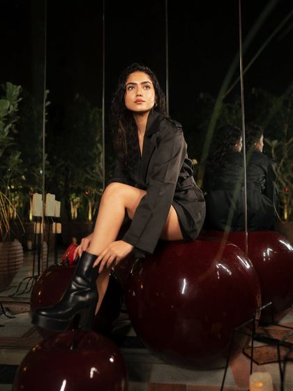 A creative on-location shot using large, reflective cherry sculptures as a prop. The reflections and the unique setting make for a memorable and artistic fashion image.