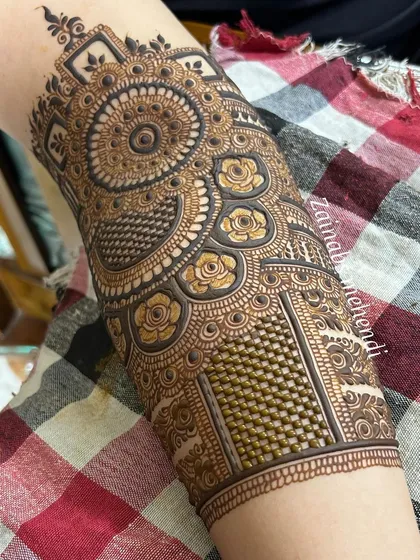 A close-up of the forearm portion of Hibah's Pakistani bridal henna, featuring a large mandala and intricate net work.