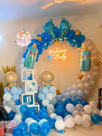 A 'Welcome Baby' boy setup with a blue and white balloon ring, neon sign, and 'BABY' blocks.