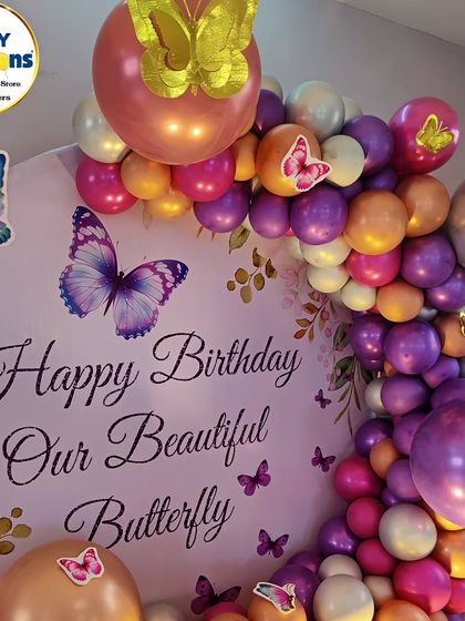 A close-up of a butterfly-themed backdrop, with a 'Happy Birthday Our Beautiful Butterfly' message.