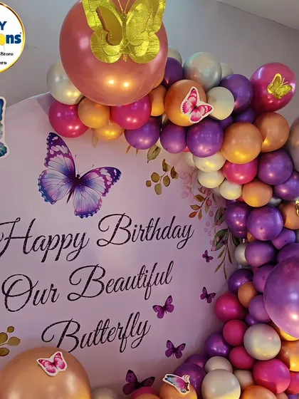 A close-up of a butterfly-themed backdrop, with a 'Happy Birthday Our Beautiful Butterfly' message.