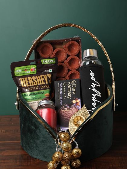 A duplicate of ID 130, this classic Diwali hamper in a green velvet basket features a set of terracotta diyas, a personalized bottle, a scented candle, and various chocolates.