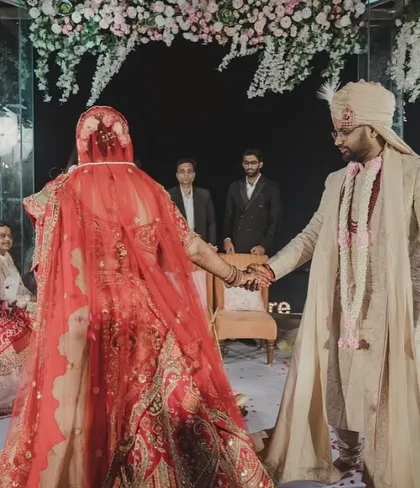 A close-up of the couple during their pheras. The decor, with its hanging floral ceiling and scattered petals on the floor, creates a sacred and beautiful space for this important ritual.
