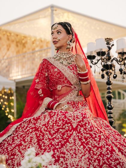 A majestic bridal portrait. The makeup features a sharp, winged eyeliner and contoured cheeks to create a sculpted, high-fashion bridal look.