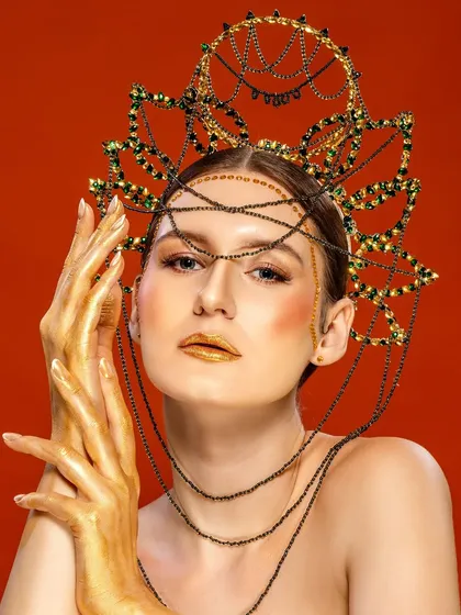 A striking editorial shot of a model with golden hands and a dramatic headpiece, looking directly at the camera. This type of powerful, artistic imagery is designed to be unforgettable and make a strong brand statement.