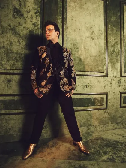 A celebrity-inspired look featuring a black tuxedo jacket with intricate all-over Zardozi embroidery in gold tones.