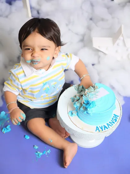 A very expressive moment from a first birthday cake smash. Even with cake all over his face, this little guy's personality shines through.