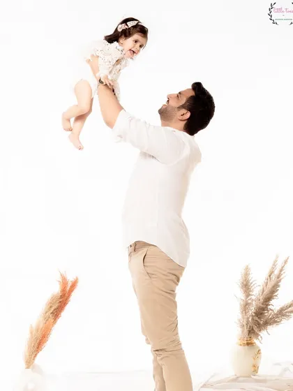 A father lifts his daughter high in the air, both of them smiling. This action shot is full of joy and captures the special, playful bond between a father and his child.