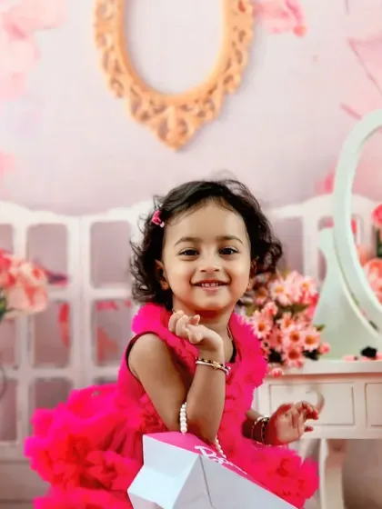 A little girl in a bright pink dress plays at a vanity table in our Barbie-themed room, full of flowers and pink accessories.